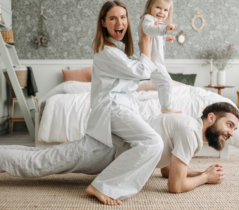 A cheerful family enjoys bonding and playing together on a cozy morning in a stylish bedroom.