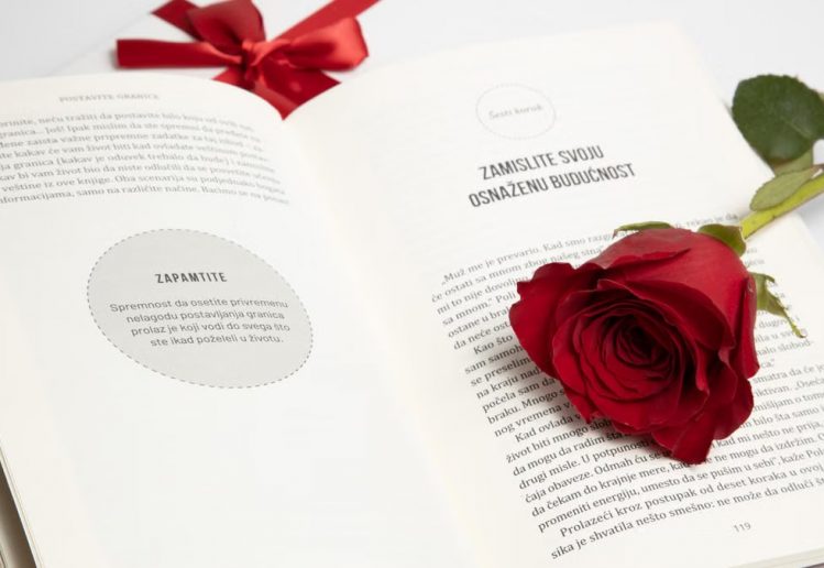 Elegant red rose on an open book with a red ribbon, symbolizing romance and literature.